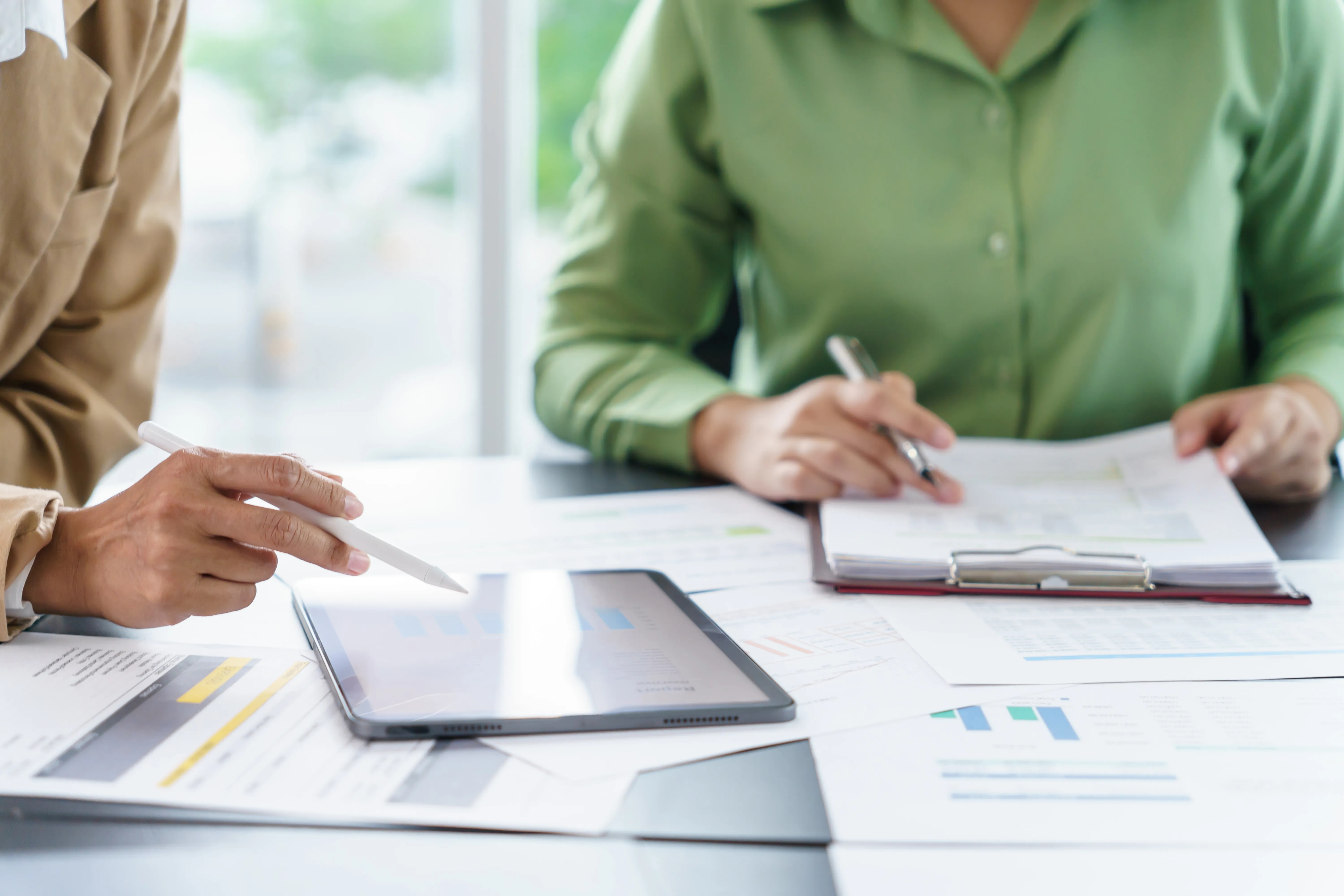 Two colleagues reviewing printed charts and tablet data during a financial planning discussion.