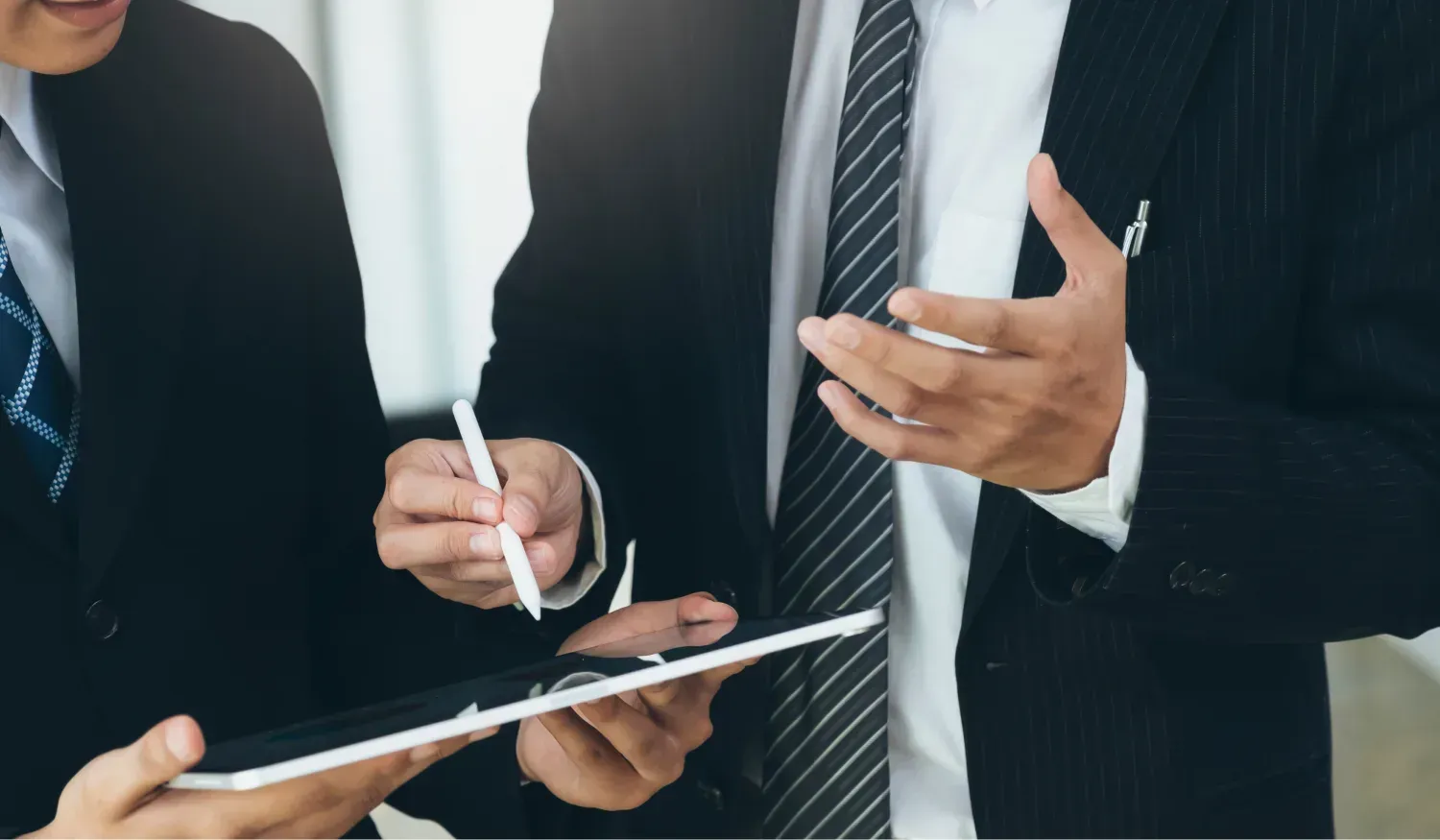 Business advisors discuss bookkeeping and management reporting needs using a tablet.