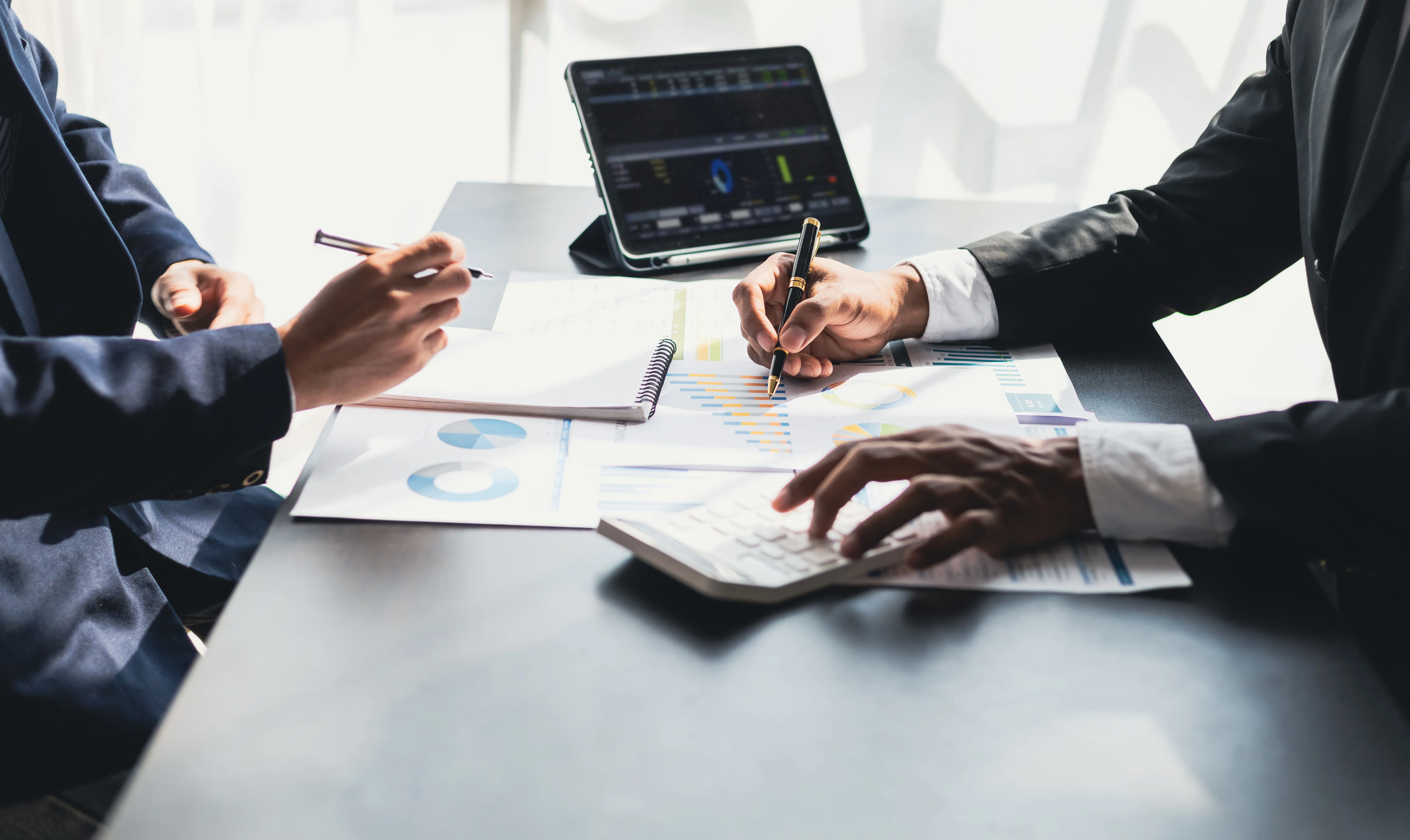 Business advisors review financial reports and cash-flow data during financial due diligence for an acquisition.
