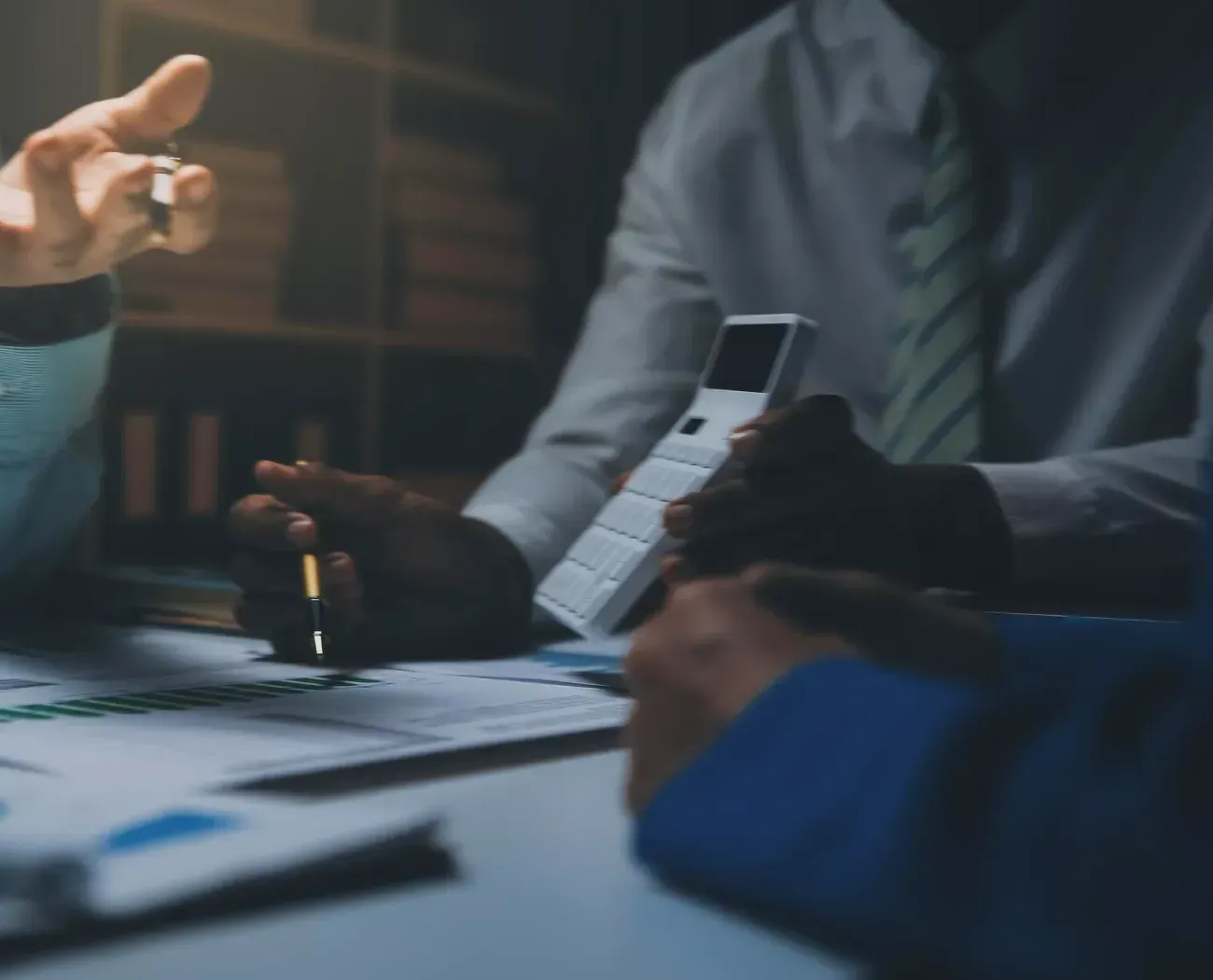 Corporate finance advisors review acquisition figures and financing capacity using a calculator.